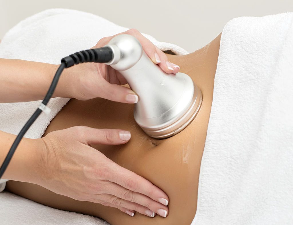 Woman getting ultrasonic and laser abdomen treatment at beauty salon.